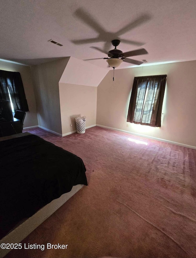 unfurnished bedroom with visible vents, baseboards, carpet, vaulted ceiling, and a textured ceiling