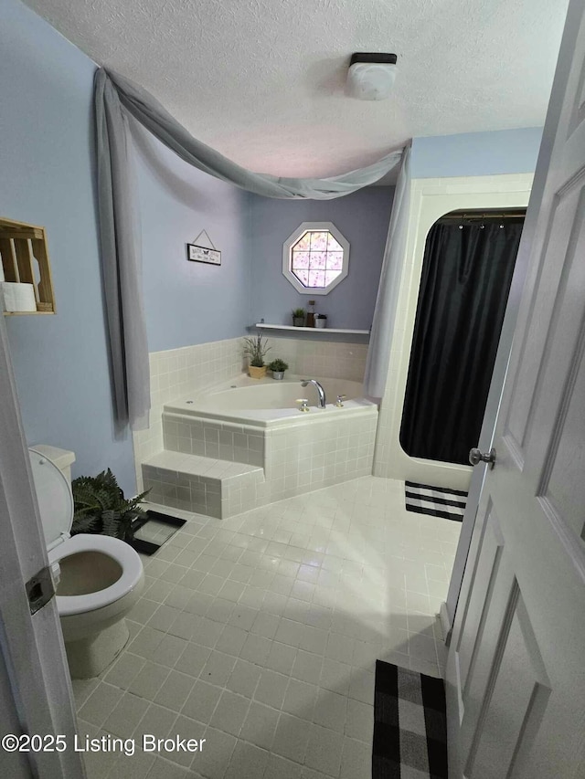 bathroom with tile patterned flooring, a textured ceiling, toilet, and a garden tub