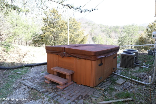 view of yard with central AC unit, a view of trees, and a hot tub