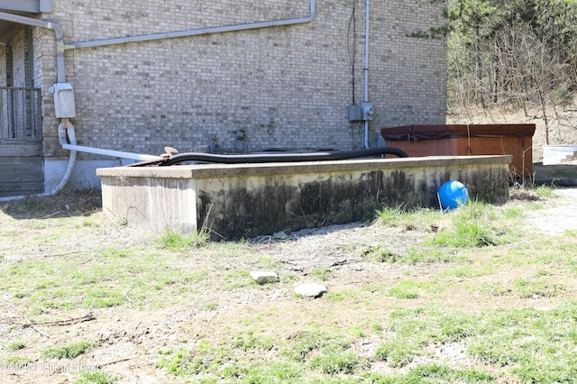 exterior space featuring a jacuzzi, brick siding, and electric meter
