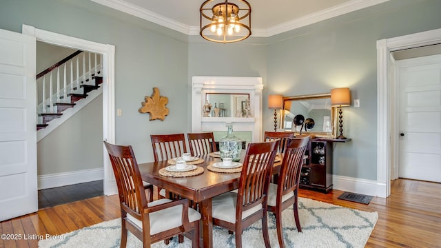 4742 Southern Pkwy, Louisville, KY 40214 - dining space featuring stairs, a notable chandelier, wood-type flooring, baseboards, and ornamental molding