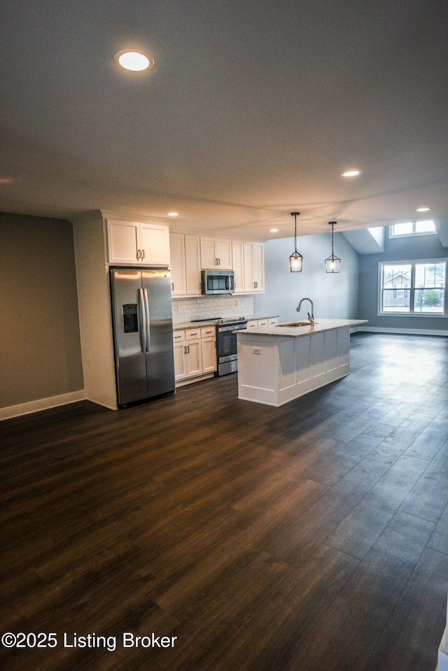 kitchen with dark wood-style floors, a sink, decorative backsplash, white cabinets, and appliances with stainless steel finishes