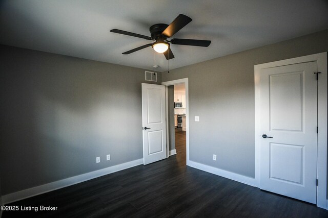 unfurnished bedroom featuring dark wood-type flooring, baseboards, visible vents, and ceiling fan