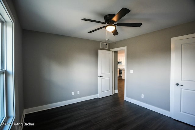 unfurnished bedroom with visible vents, a ceiling fan, dark wood-type flooring, and baseboards