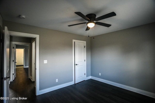 unfurnished bedroom featuring dark wood finished floors, a ceiling fan, and baseboards