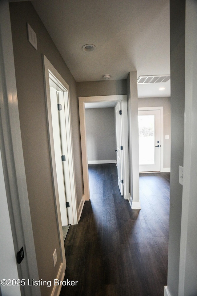 corridor featuring dark wood finished floors, visible vents, and baseboards