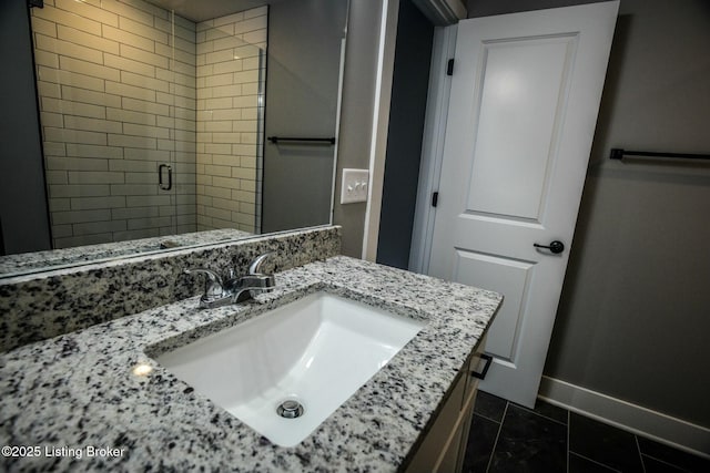 bathroom featuring a stall shower, vanity, and baseboards