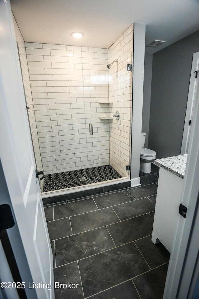 bathroom with vanity, a shower stall, toilet, and visible vents