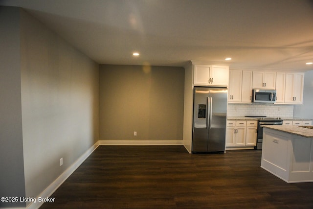 kitchen with light stone counters, dark wood-style floors, stainless steel appliances, decorative backsplash, and white cabinetry