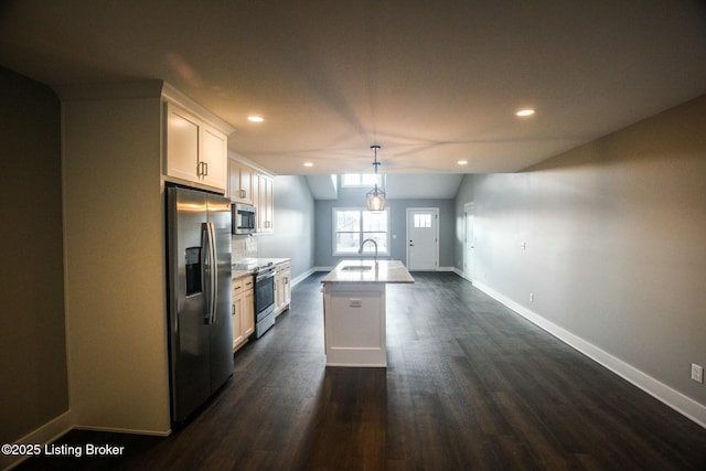 kitchen with dark wood-style flooring, a kitchen island with sink, a sink, appliances with stainless steel finishes, and white cabinetry
