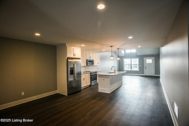 kitchen with a center island with sink, light countertops, appliances with stainless steel finishes, white cabinets, and dark wood-style flooring
