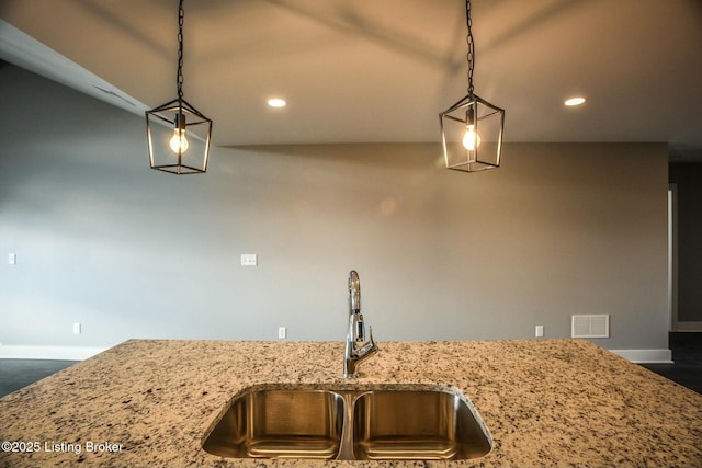interior details with light stone counters, baseboards, visible vents, recessed lighting, and a sink