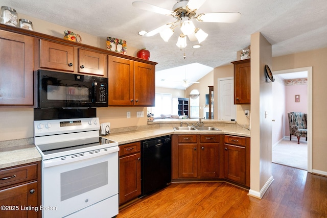 kitchen with light countertops, a sink, light wood finished floors, a ceiling fan, and black appliances