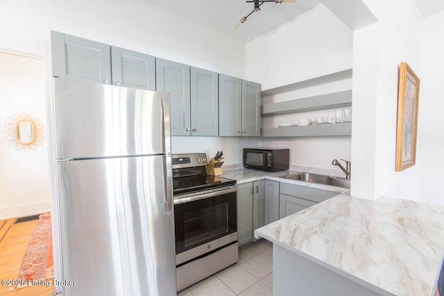 kitchen with light tile patterned floors, light stone countertops, open shelves, a sink, and appliances with stainless steel finishes