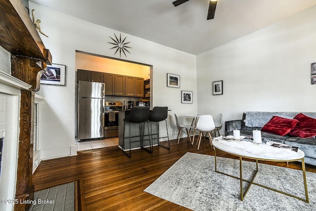 living area featuring a fireplace, light wood-style flooring, a ceiling fan, and baseboards
