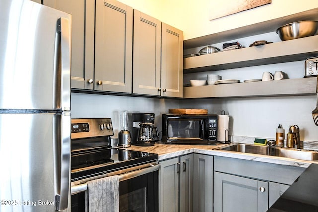 kitchen featuring appliances with stainless steel finishes, light countertops, gray cabinetry, and open shelves