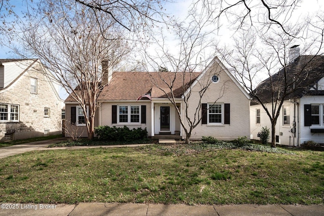 view of front facade with a chimney, a front lawn, and brick siding