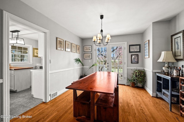 dining area featuring light wood-style flooring, a chandelier, and visible vents