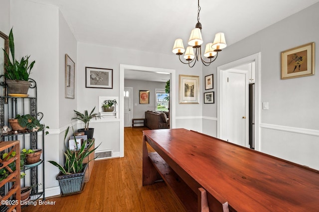 dining space featuring visible vents, wood finished floors, and a notable chandelier