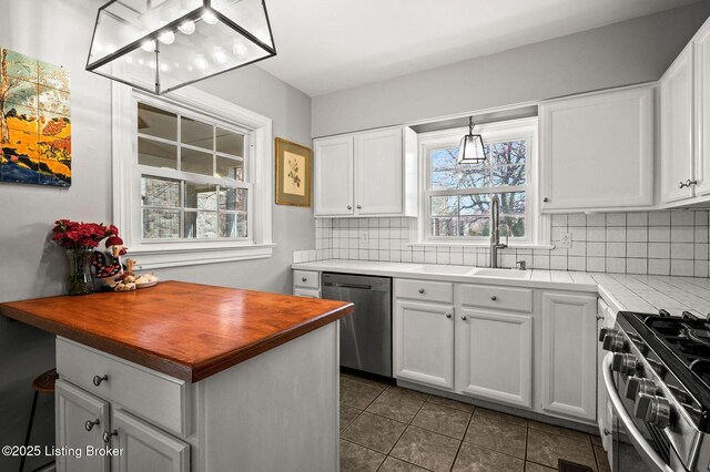 kitchen featuring butcher block countertops, stainless steel appliances, dark tile patterned floors, backsplash, and white cabinets