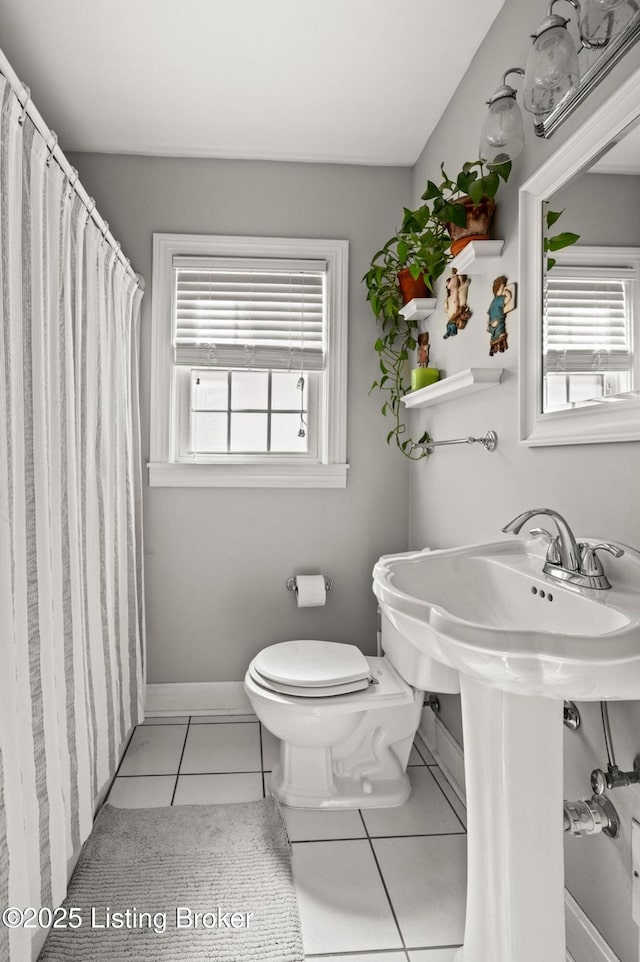 bathroom featuring a shower with curtain, baseboards, toilet, and tile patterned flooring