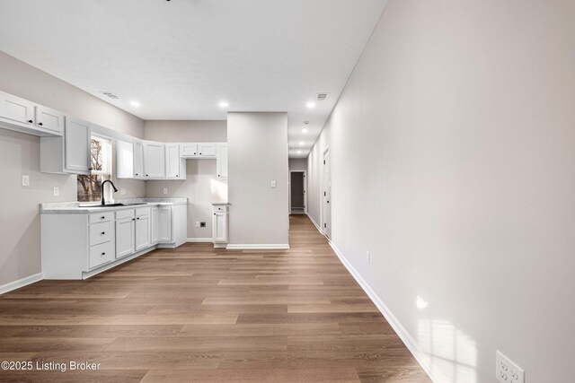 2064 Emmet Ave, Louisville, KY 40217 - kitchen with baseboards, visible vents, light wood finished floors, a sink, and white cabinetry