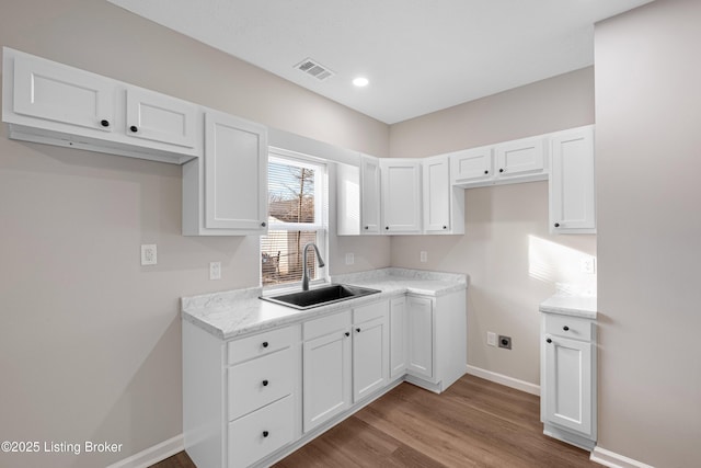 2064 Emmet Ave, Louisville, KY 40217 - kitchen with visible vents, a sink, wood finished floors, white cabinets, and baseboards
