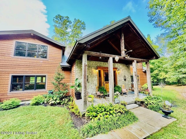 back of property with stone siding and a lawn