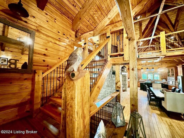 stairway featuring high vaulted ceiling, wood ceiling, wooden walls, wood-type flooring, and beam ceiling