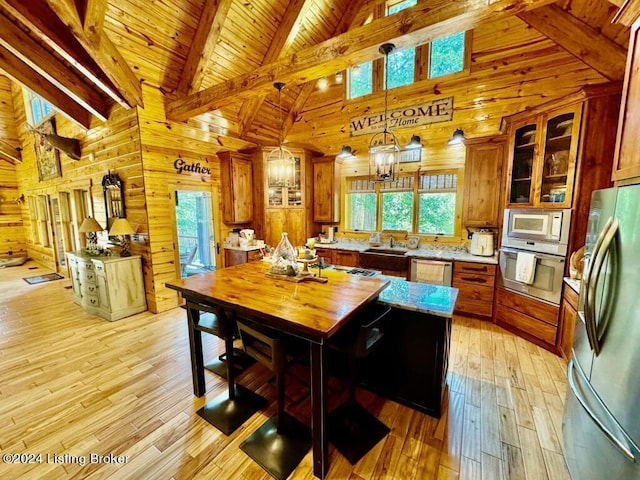 kitchen featuring wood walls, light wood finished floors, brown cabinets, and appliances with stainless steel finishes