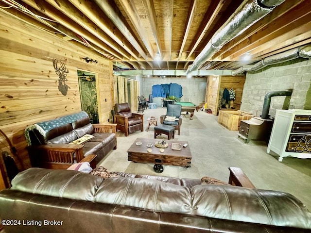 unfinished basement featuring wood walls, a wood stove, and concrete block wall