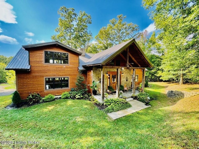 back of property featuring a yard, metal roof, and a patio area