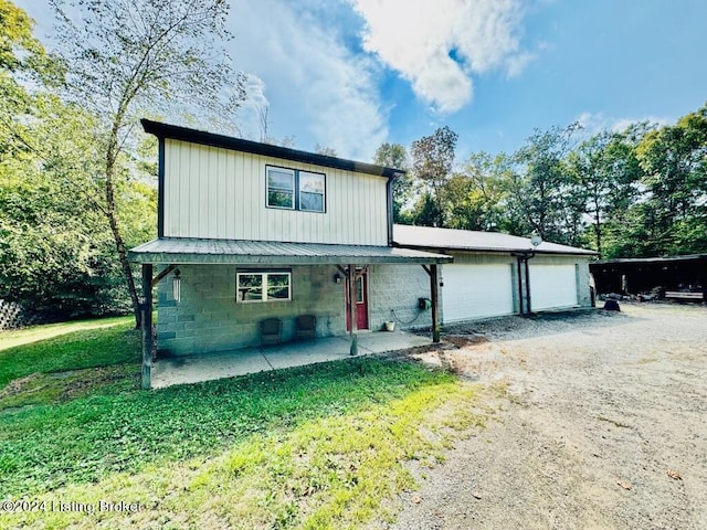 view of front of home with board and batten siding, metal roof, a patio area, a garage, and driveway