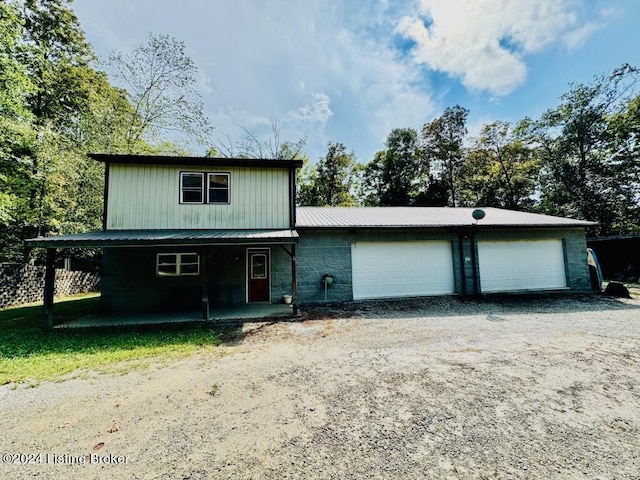 view of front of house with driveway, metal roof, a garage, and a porch