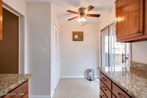 3307 Leith Ln Apt 3, Louisville, KY 40218 - kitchen featuring light stone counters, brown cabinets, light tile patterned flooring, and a ceiling fan