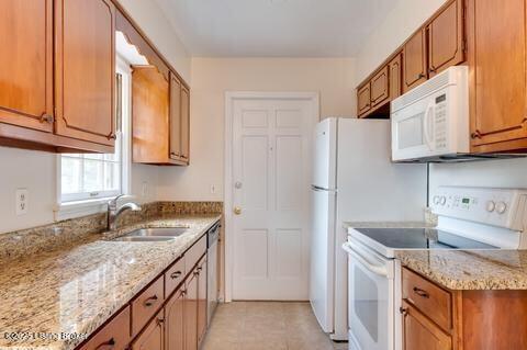 3307 Leith Ln Apt 3, Louisville, KY 40218 - kitchen featuring brown cabinetry, white appliances, light stone counters, and a sink