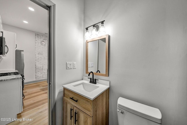 bathroom with toilet, vanity, recessed lighting, and wood finished floors