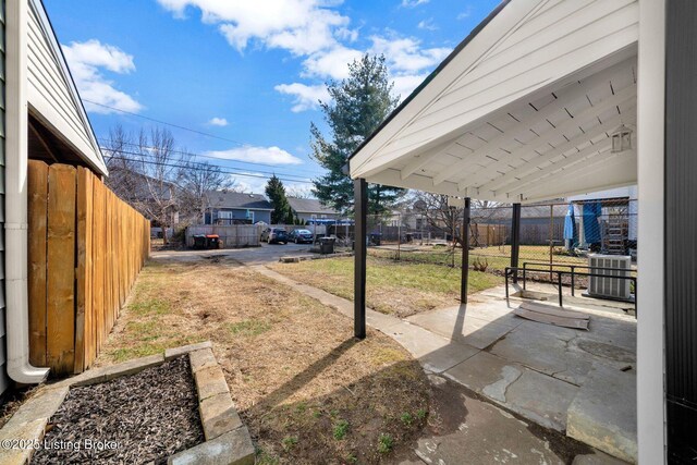view of yard featuring central air condition unit, fence, a patio, and a residential view
