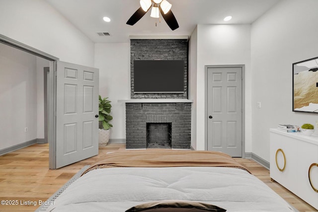 bedroom featuring a fireplace, light wood-type flooring, baseboards, visible vents, and ceiling fan