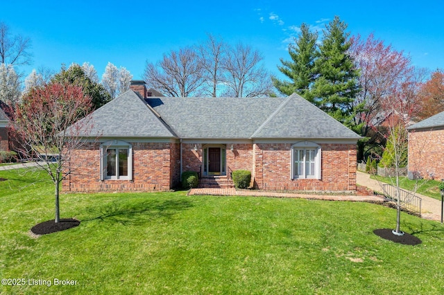 single story home featuring a chimney, brick siding, a shingled roof, and a front yard