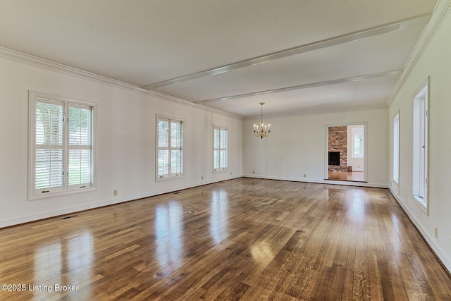empty room featuring hardwood / wood-style flooring, ornamental molding, baseboards, and a notable chandelier