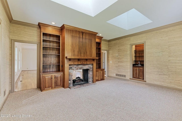 unfurnished living room with visible vents, carpet, a skylight, a brick fireplace, and crown molding
