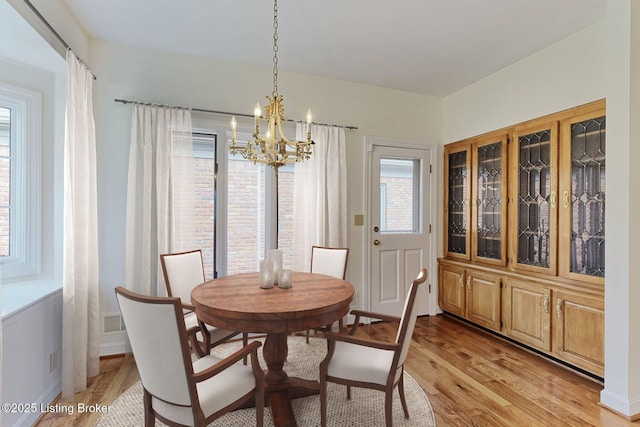 dining area featuring a chandelier, visible vents, and light wood finished floors