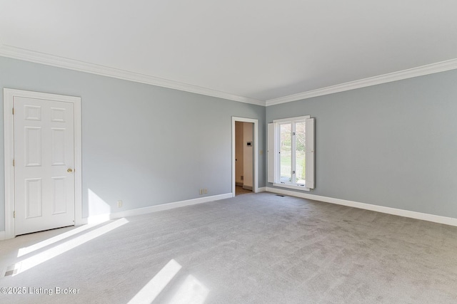 carpeted spare room featuring crown molding and baseboards