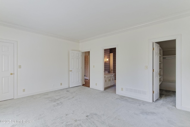 unfurnished bedroom with carpet flooring, visible vents, a spacious closet, and ornamental molding