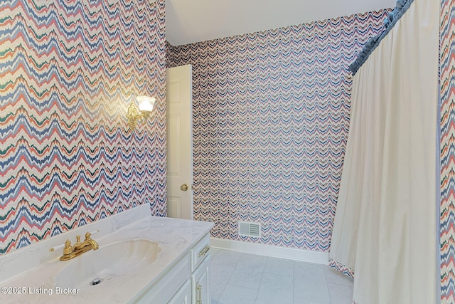 bathroom with wallpapered walls, tile patterned floors, visible vents, a sink, and baseboards