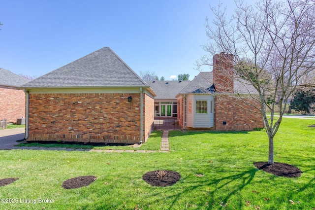 back of house with a lawn, brick siding, central air condition unit, and a chimney