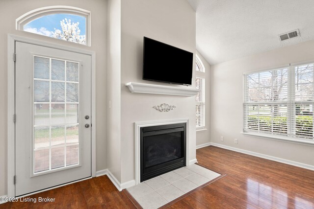 135C Michelle Dr, Shepherdsville, KY 40165 - unfurnished living room with baseboards, a fireplace with flush hearth, wood finished floors, lofted ceiling, and visible vents