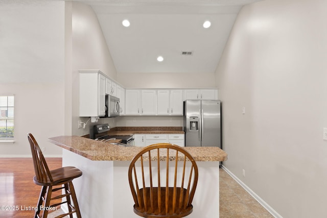 135C Michelle Dr, Shepherdsville, KY 40165 - kitchen with visible vents, a breakfast bar, white cabinetry, appliances with stainless steel finishes, and vaulted ceiling