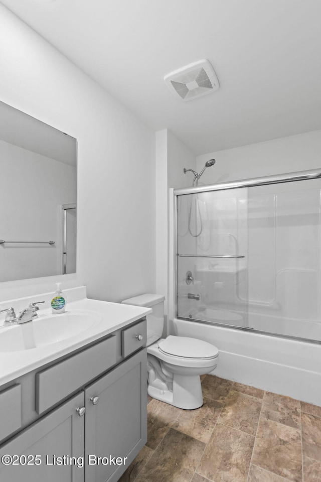 243 Zelcova Dr, Eminence, KY 40019 - full bath featuring vanity, toilet, stone finish floor, visible vents, and bath / shower combo with glass door
